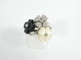 un gros plan d'une bague posée sur une surface blanche, avec des fleurs noires et blanches