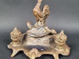 a statue of a rooster sitting on top of a bowl