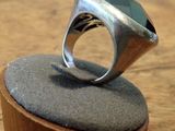 a silver ring with a green stone on top of a wooden stand