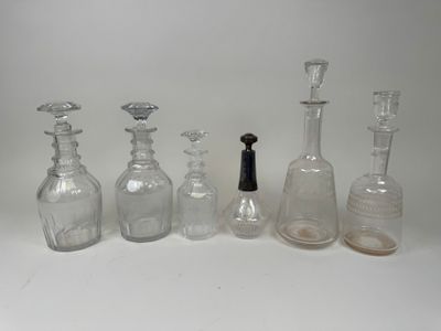 five glass bottles and a bottle stopper on a white surface