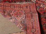 a red rug on the floor next to a wall