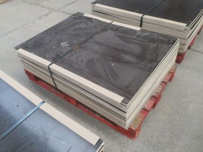 plusieurs piles de tôles métalliques posées sur des palettes, sur un sol en béton