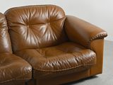 a brown leather couch sitting in a corner of a room