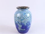 un vase bleu avec un couvercle argenté sur fond blanc
