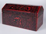 une boîte rouge et noire posée sur une surface blanche
