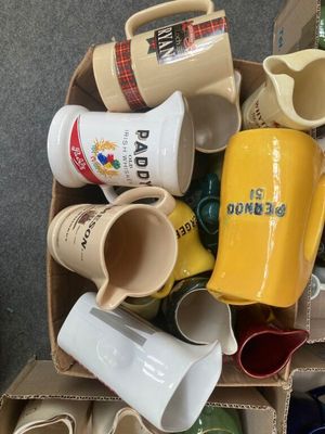 une boîte remplie de tasses à café et de mugs posée par terre