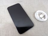 a black cell phone with a charger on the table