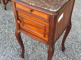two small tables with marble tops sit on gravel near a chair