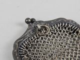 a silver purse with a chain around it on a white surface