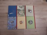four notebooks are lined up on a wooden floor with pictures on them