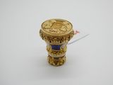 une image représentant un vase bleu et doré posé sur une surface blanche