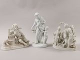 three white figurines of a woman and a man with a dog