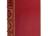 un vieux livre avec une couverture rouge et des bordures dorées sur fond blanc