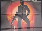 movie poster of a man in a suit holding a gun in front of a building