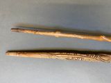 two wooden sticks with carvings on them sitting next to each other
