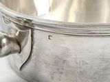 a silver bowl with a handle on a white surface