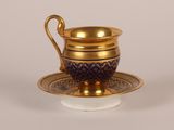 une tasse et une soucoupe dorées et bleues posées sur une soucoupe