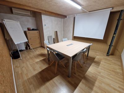 une salle équipée d'une table, de chaises et d'un écran de projection