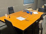 une table avec des chaises et un ordinateur portable posé dessus, dans une pièce