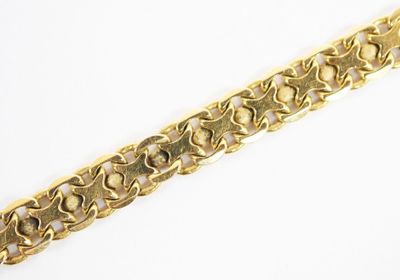 gros plan d'un bracelet en or sur une surface blanche