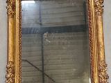 a gold framed mirror hanging on a wall in a room