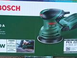 le boîtier d'une ponceuse orbitale Bosch PX220A posé sur une surface en bois
