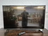 un téléviseur posé sur une table en bois, avec une télécommande dessus