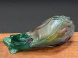 a glass sculpture of a frog sitting on a wooden table