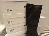 des bottes en cuir noir toutes neuves, avec un talon doré et des fermetures éclair