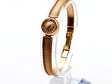 une montre en or posée sur un socle transparent, sur un fond blanc