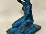 a blue statue of a woman sitting on a square base