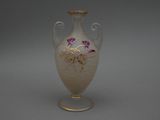 un vase blanc orné de fleurs violettes, posé sur une table