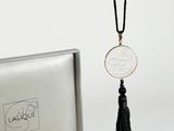 a close up of a necklace with a coin and a tassel