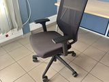 a black office chair sitting in front of a computer desk