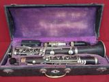 a black and silver clarinet in a case on a red background
