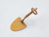 un petit objet métallique avec une poignée en bois sur une surface blanche