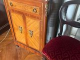 a red chair sitting next to a wooden cabinet