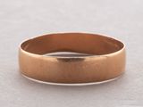 a close up of a gold wedding ring on a white surface