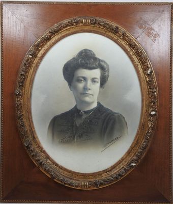 une vieille photo d'une femme en robe noire, dans un cadre en bois