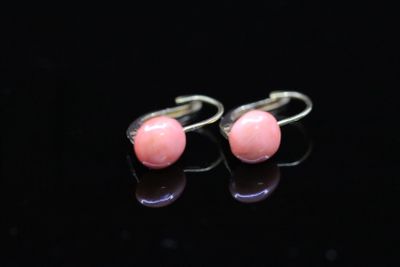 pair of pink stone earrings on black surface with reflection