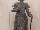 une statue représentant une femme tenant une canne, posée sur une table