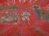 a red plate with a painting of people on it