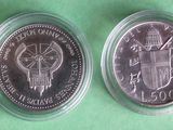 the two coins are in a clear plastic container on a green surface