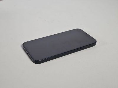 un téléphone portable noir posé sur une table blanche