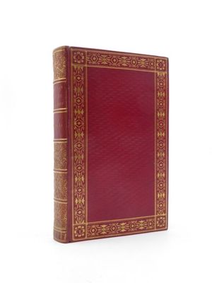 un vieux livre à la couverture rouge posé sur une surface blanche