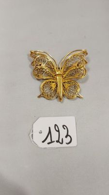 un gros plan d'un papillon doré sur une surface blanche