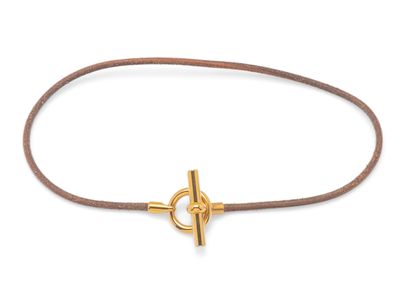 un bracelet en cuir marron orné d'une ancre plaquée or sur fond blanc