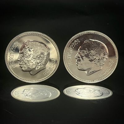 deux pièces d'argent posées l'une à côté de l'autre sur une surface noire