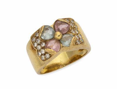 un gros plan d'une bague en or sertie de pierres roses et bleues