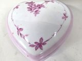 a white heart shaped box with pink flowers on it